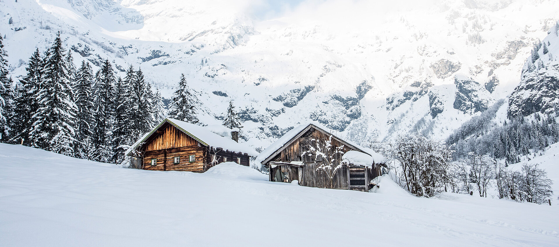 Zwei verschneite Hütten inmitten einer Winterlandschaft