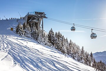 Almliesl Hüttenurlaub in den Bergen buchen Skilift, verschneite Pisten und strahlend blauer Himmel