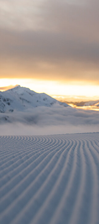 Eine frisch präparierte Piste mit Bergen im Hintergrund