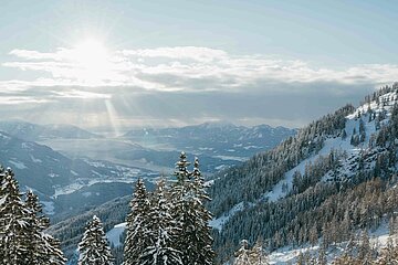 Winterurlaub in Kärnten buchen Paar beim Skitouren gehen in den verschneiten Nockbergen bei Sonnenschein