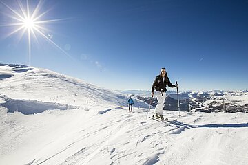 Almliesl Hüttenurlaub in den Bergen buchen Zwei motivierte Tourengeher starten bei strahlender Wintersonne in Richtung Gipfel